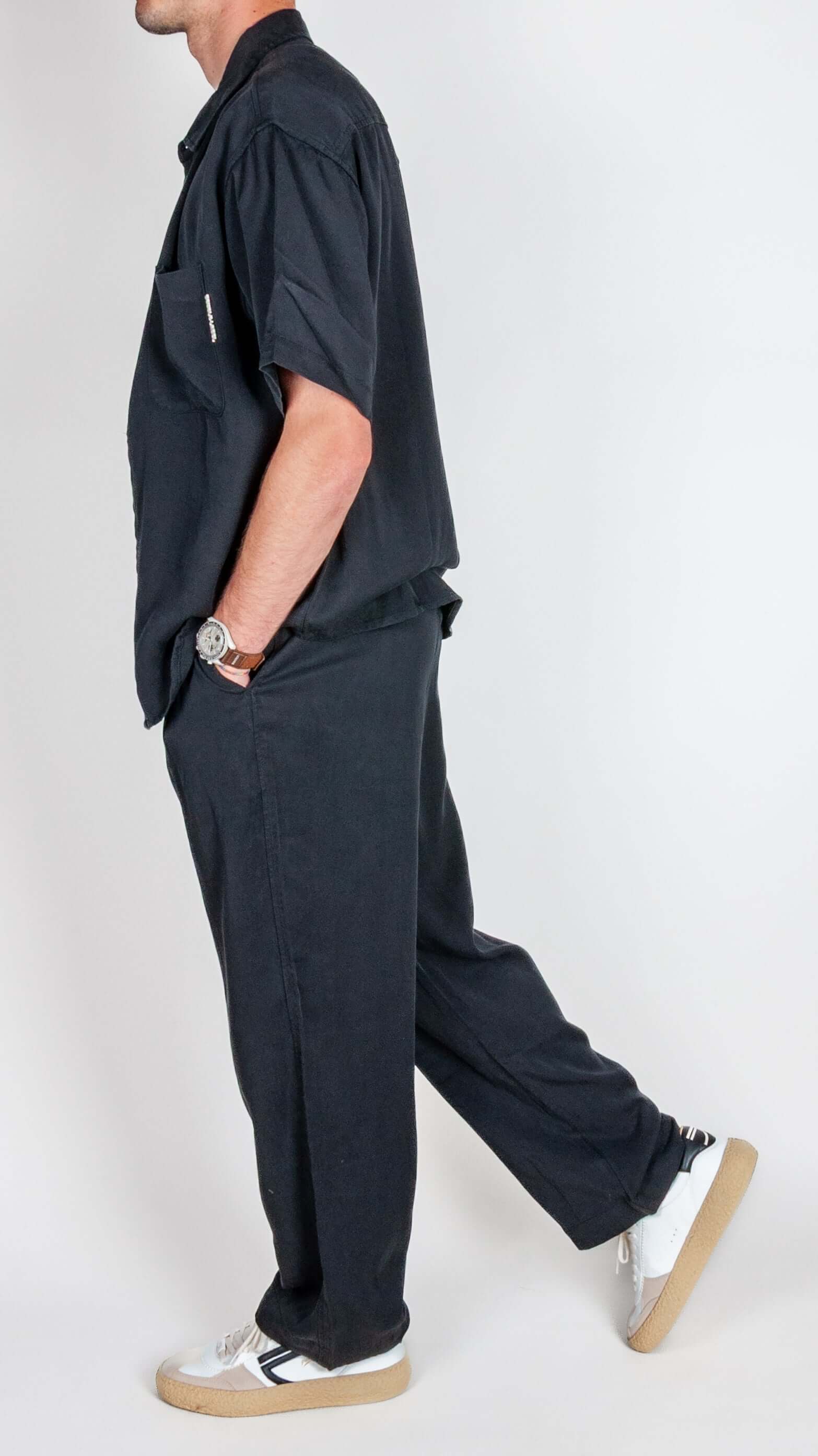 Man wearing Completo in Lyocell Double Label Nero, showcasing stylish side profile in black fabric outfit.