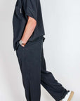Man wearing Completo in Lyocell Double Label Nero, showcasing stylish side profile in black fabric outfit.