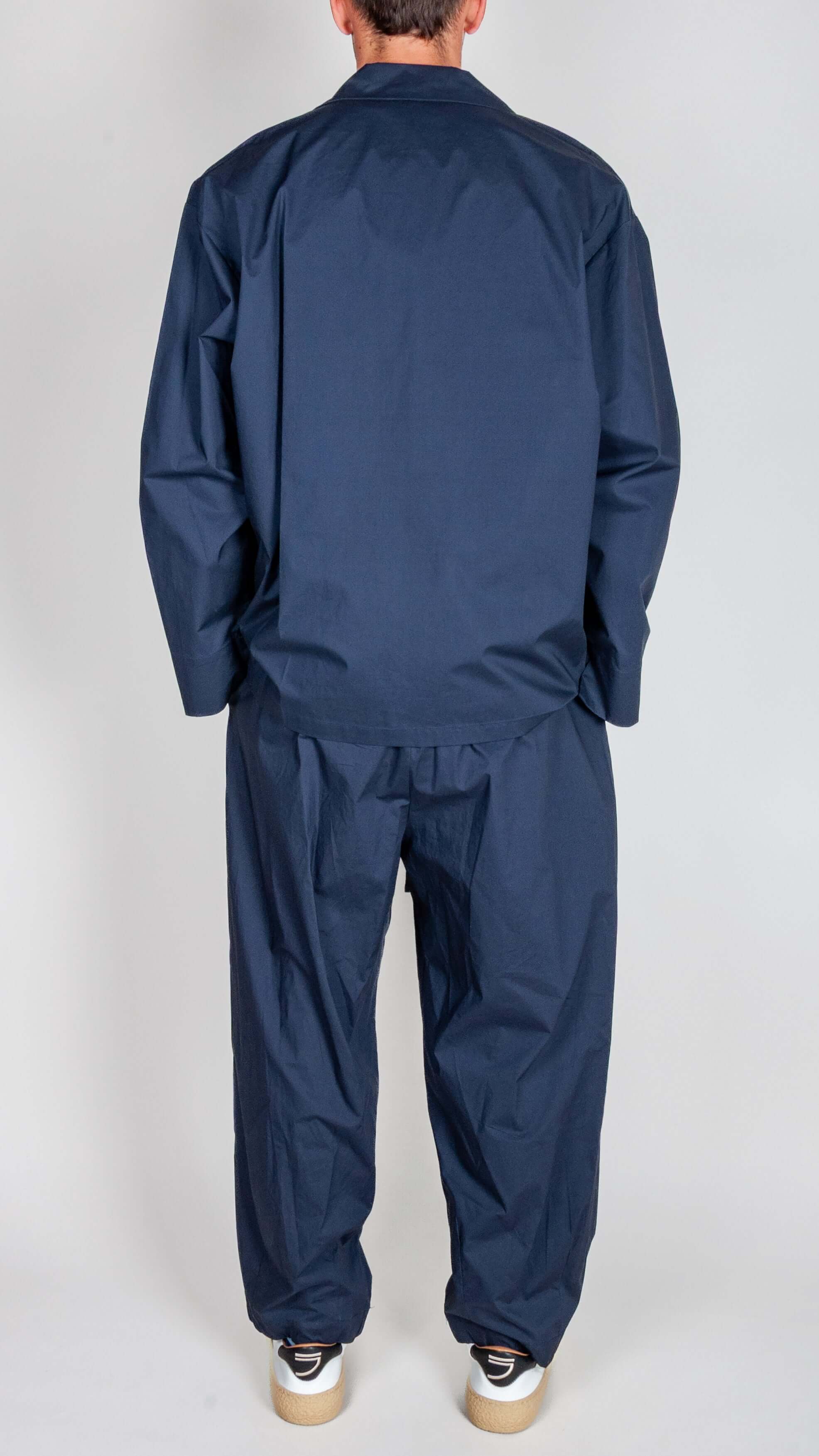 Model wearing Completo Popeline outfit in blue, showcasing the back view of the stylish two-piece set.