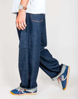 Jeans Huge Uomo Rinse Denim Amish Art, modello con jeans uomo denim ristretto e scarpe sportive.