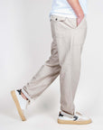 Uomo che indossa pantalone Fatigue Tela Clark in tessuto beige, taglia 48, con scarpe sportive bianche.