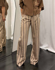 Pantaloni donna riga eleganti indossati con camicia marrone in ambiente di moda.