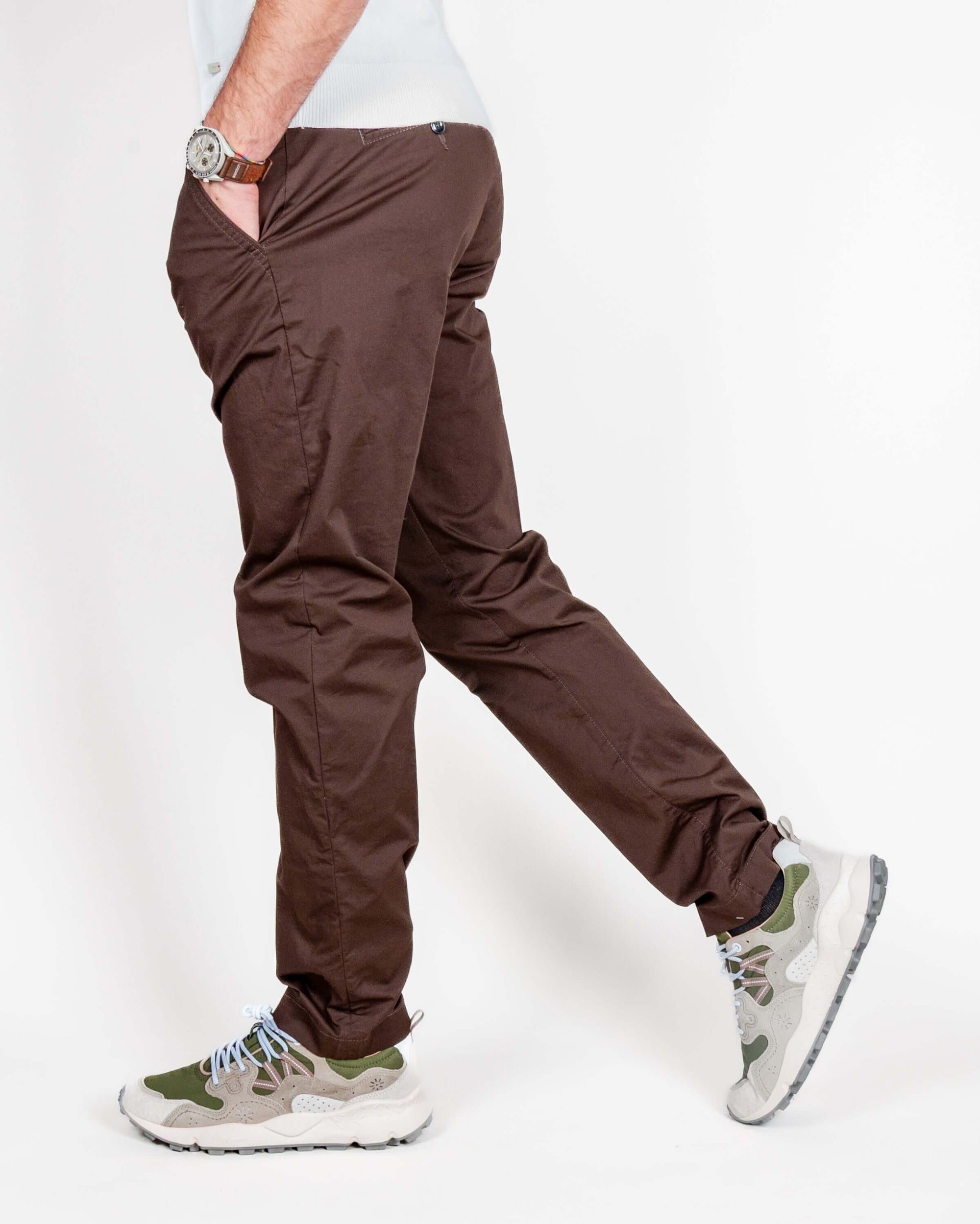 Uomo in pantalone slim fit cotone marrone Officina 36, indossando sneakers e orologio, modello elegante.